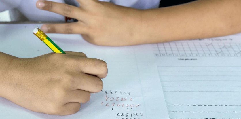 Kind telt op de vingers en schrijft rekenoefeningen op papier